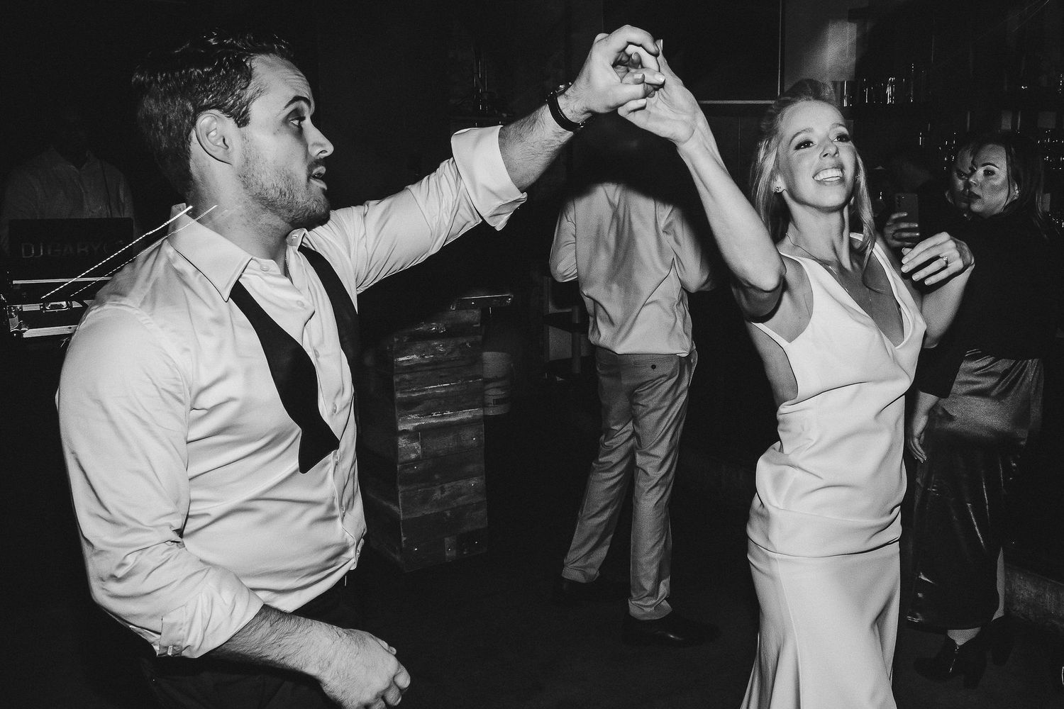 Couple twirling and dancing during wedding reception in black and white.