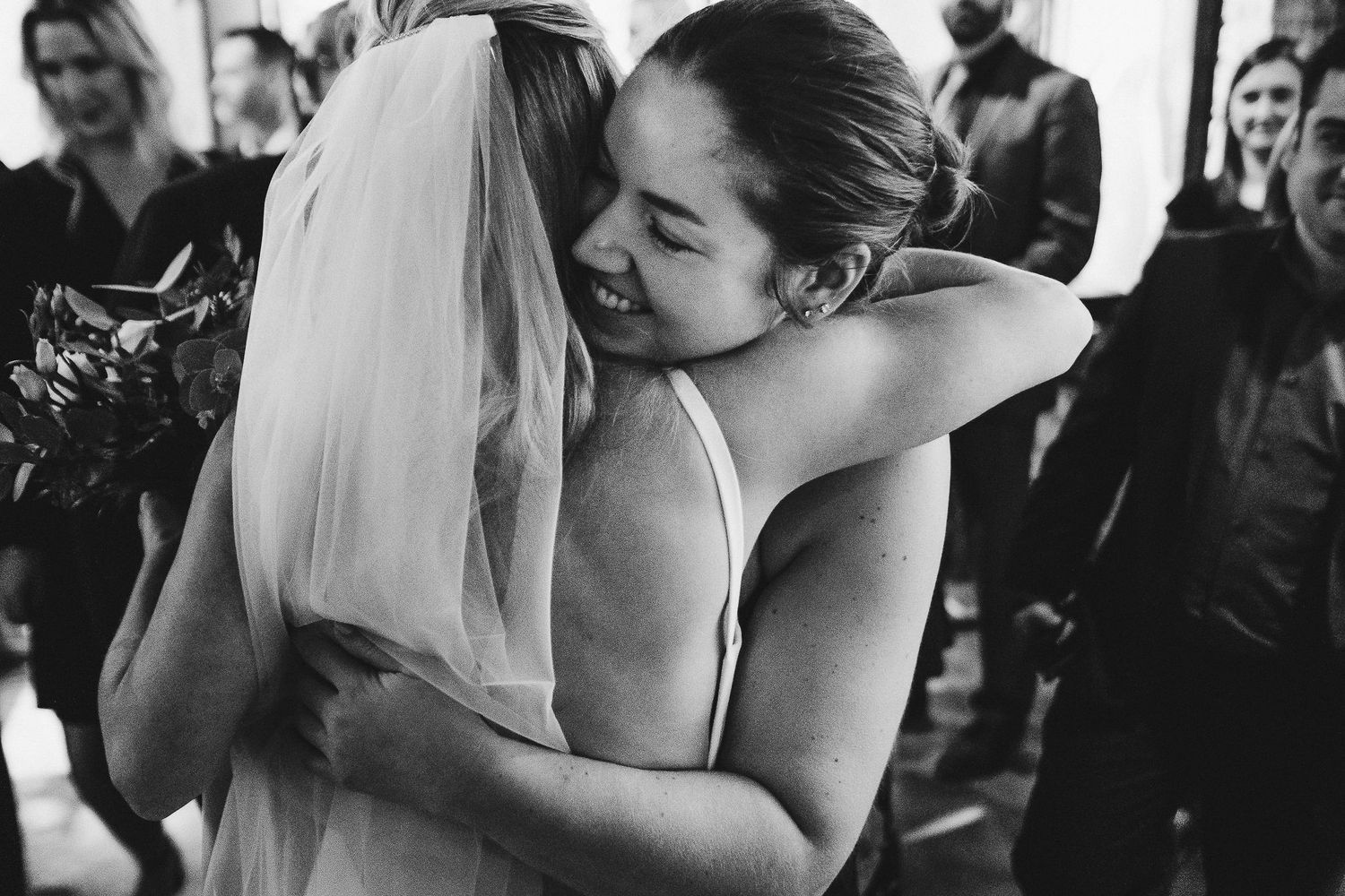 A black and white capture of an emotional wedding embrace between two people.