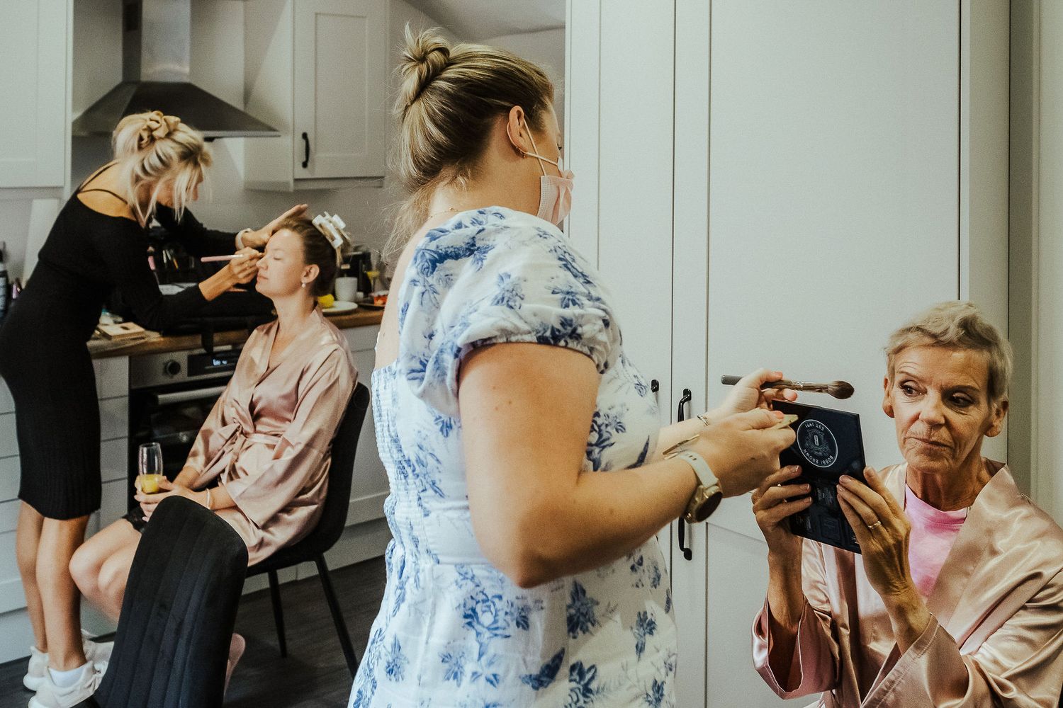 Multiple people getting hair and makeup done in preparation for an event.