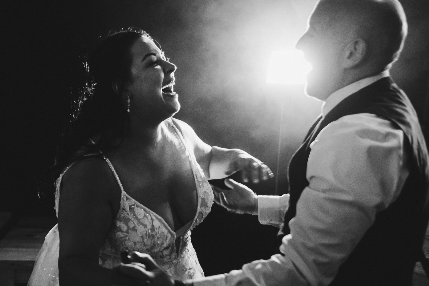 Silhouetted couples dancing together during romantic evening reception.