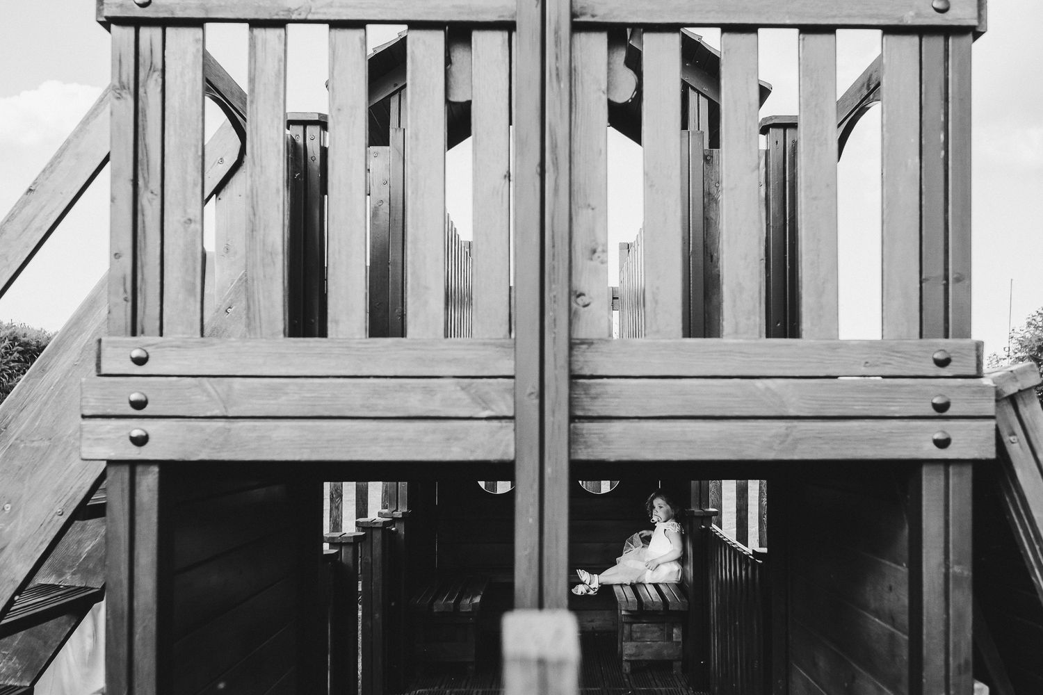 A black and white view through wooden deck railings showing architectural details.