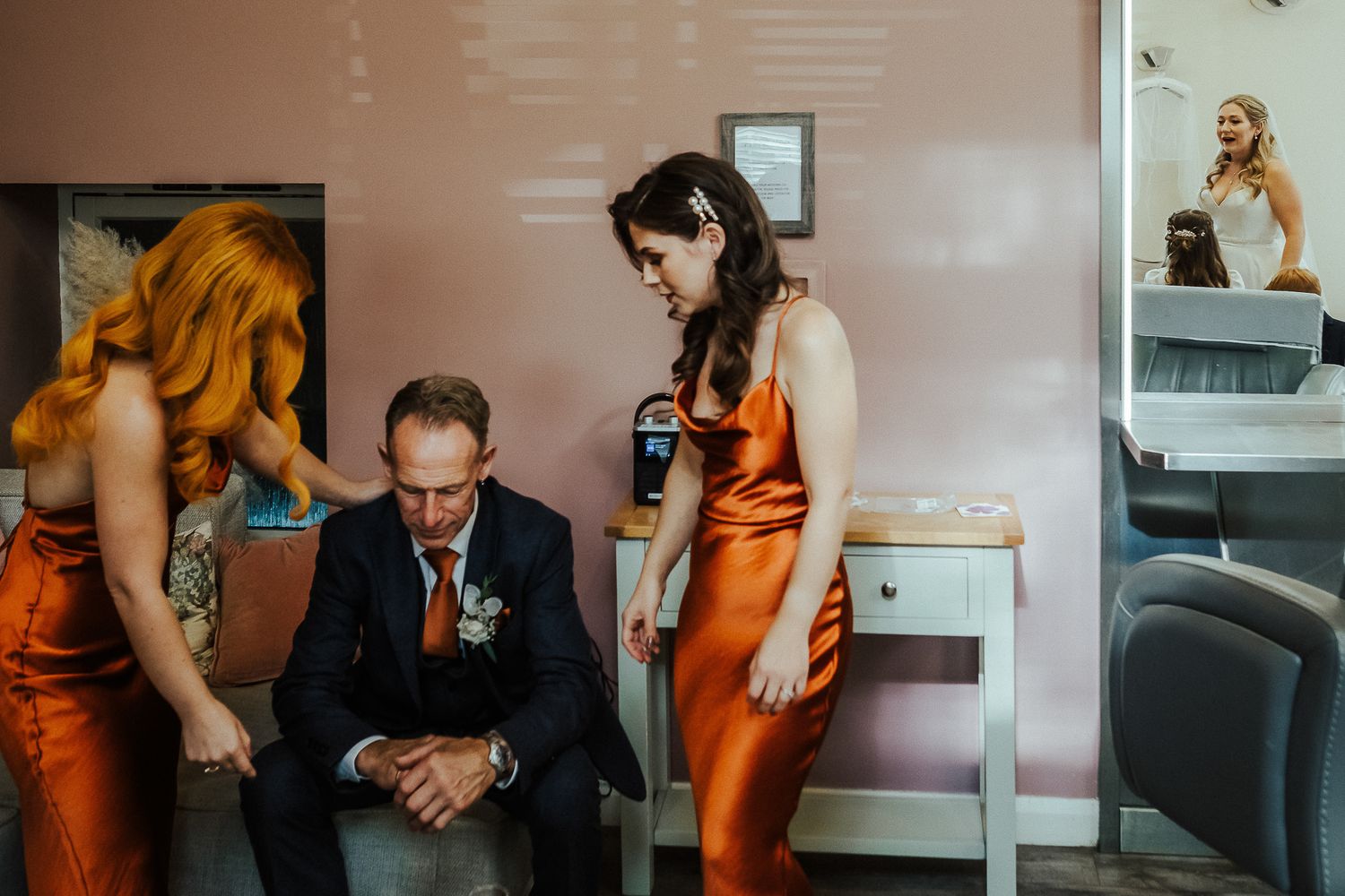 Wedding party members in burnt orange dresses during preparation.