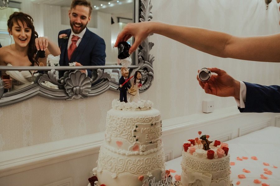 Wedding cake cutting ceremony with white tiered cake decorated with flowers.
