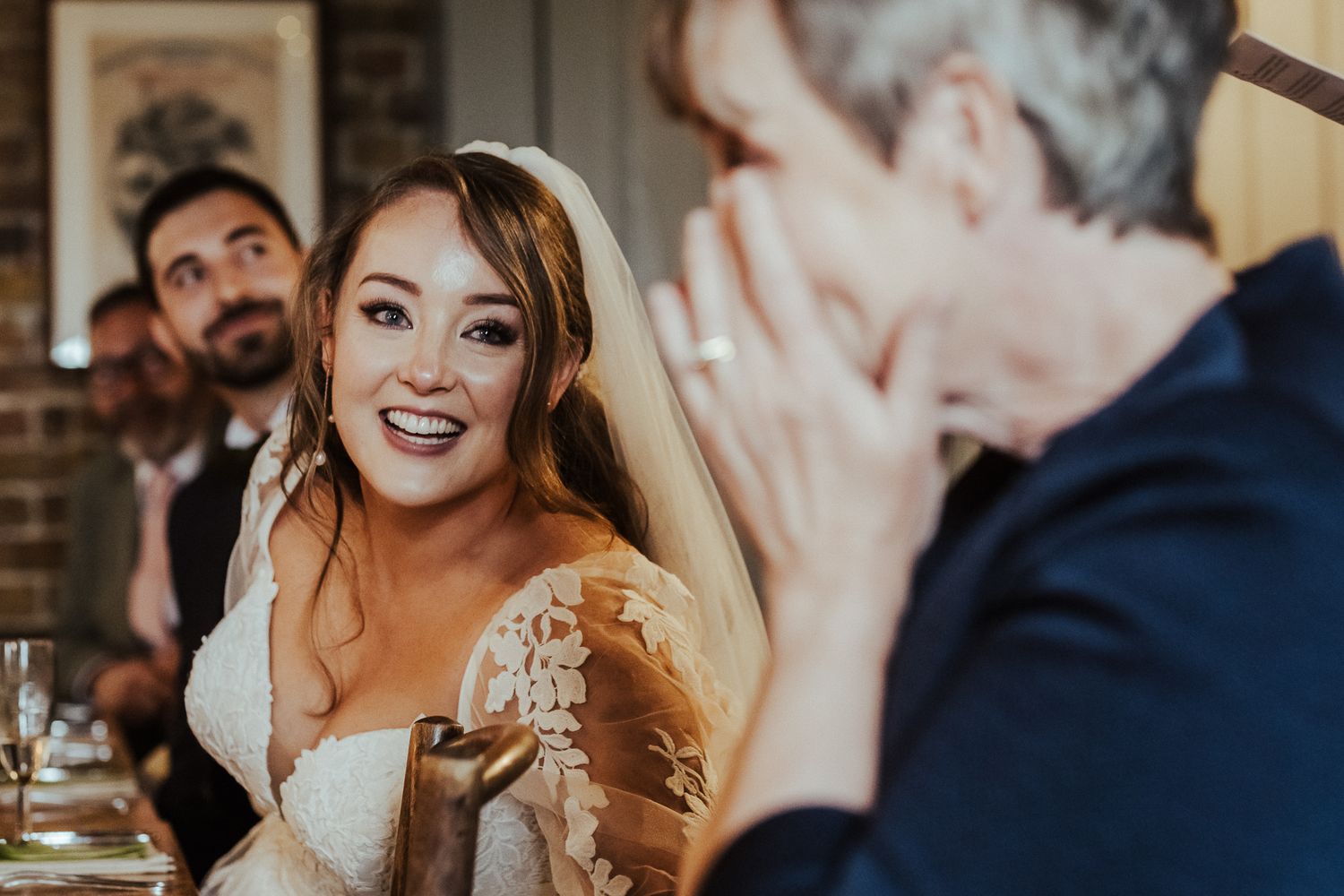 Wedding reception candid showing emotional reactions during speeches.