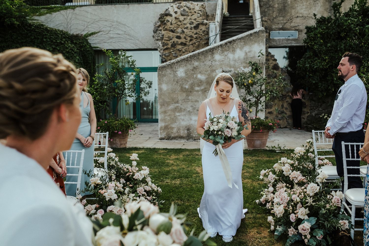 Wedding ceremony setup with white floral arrangements at a rustic stone venue.