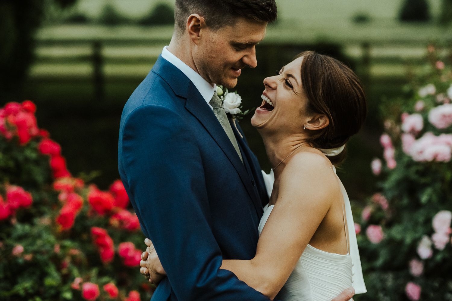 Couple sharing intimate moment among blooming roses in garden setting.