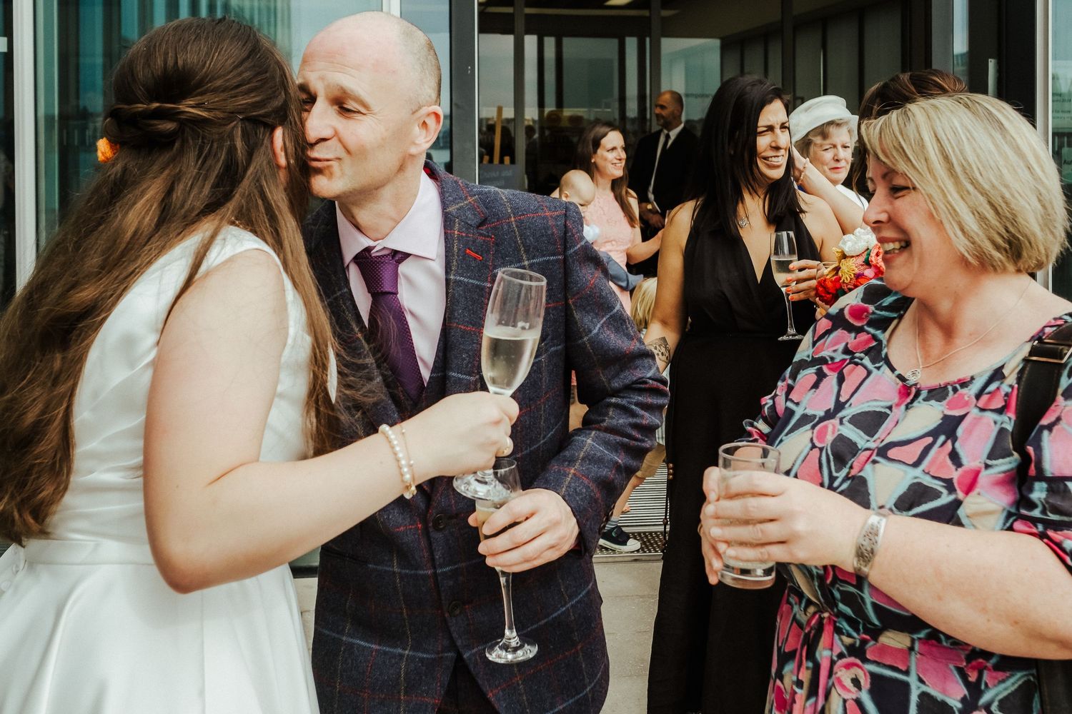 Wedding guests socialize and toast with champagne during an outdoor reception.