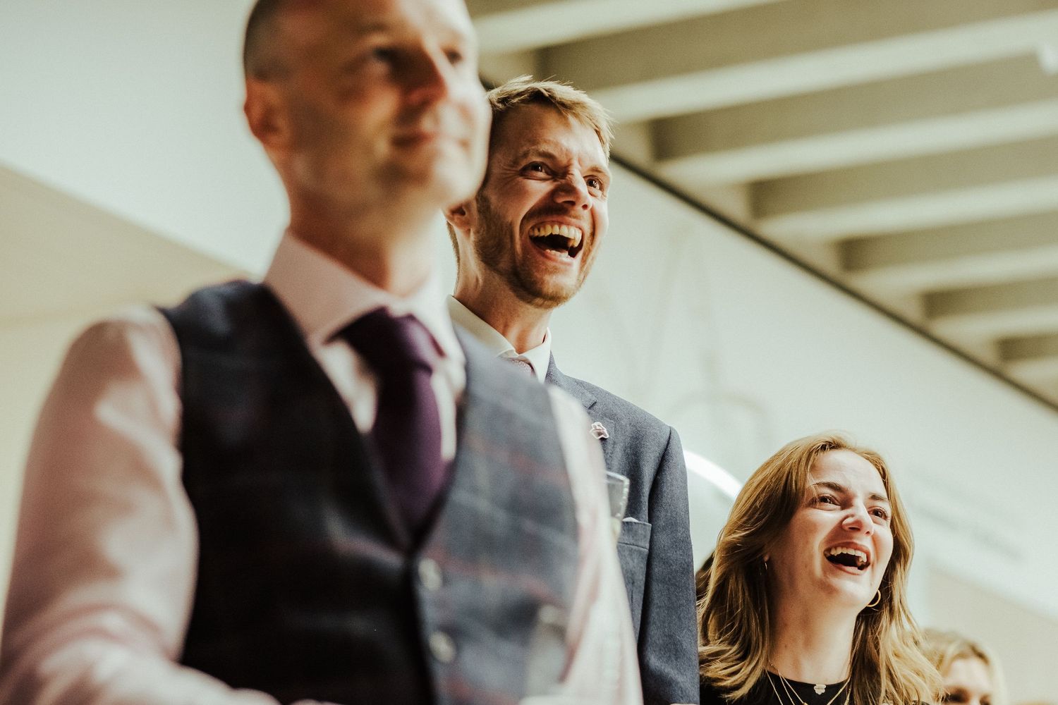 Wedding attendees share a hearty laugh during a reception celebration.
