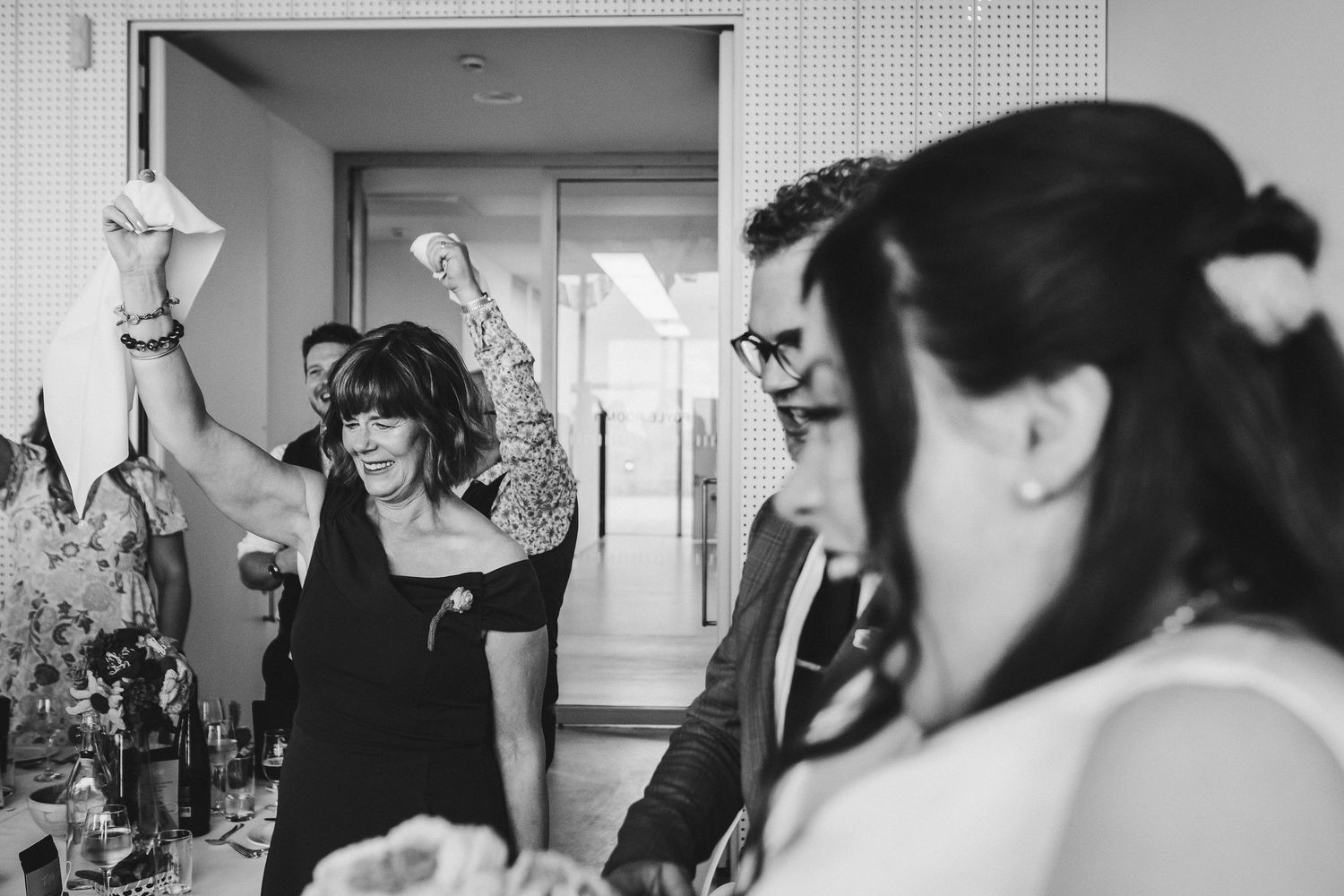 A celebratory moment at a wedding reception with guests dancing and raising their hands.