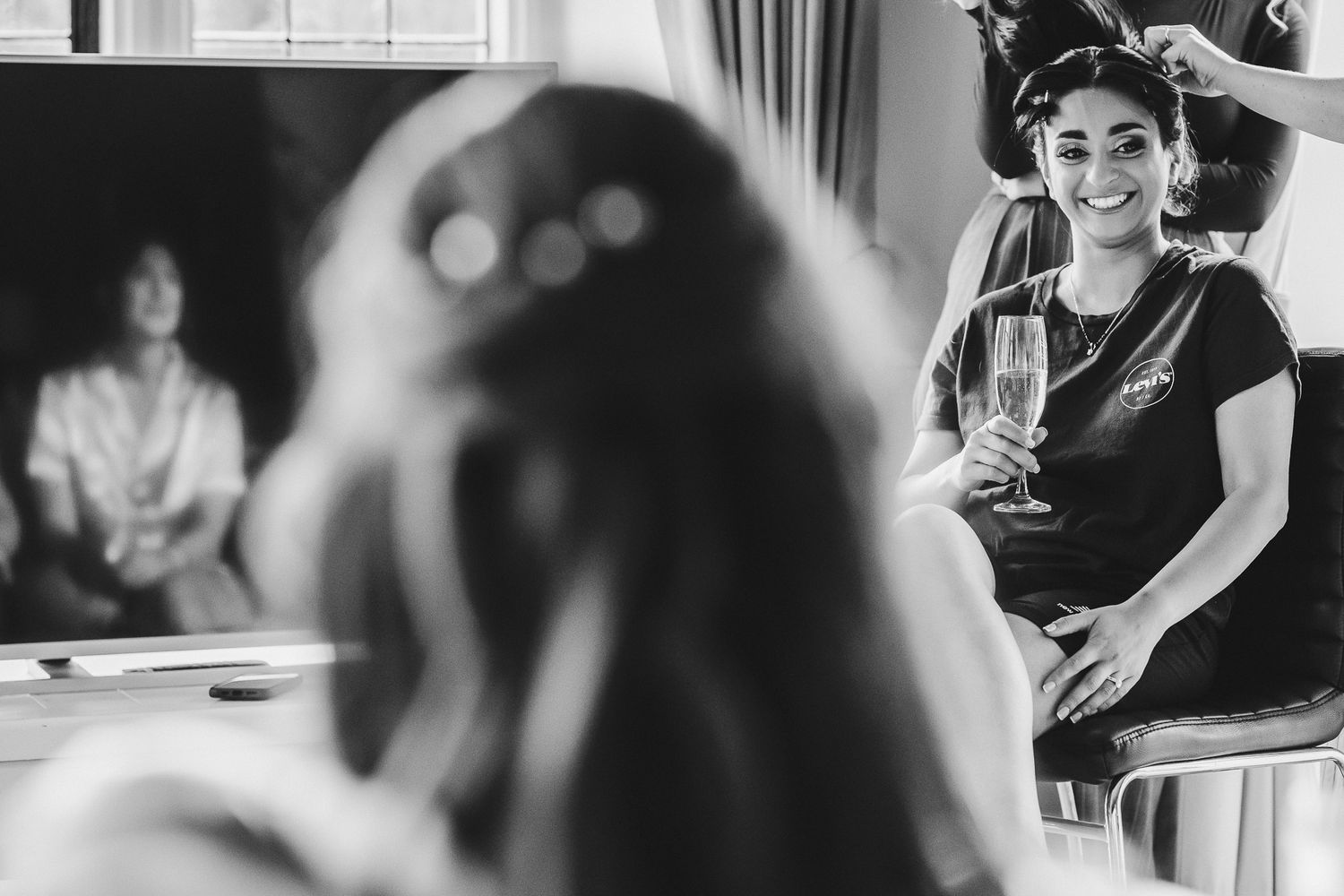 Black and white image showing reflections in makeup mirror during salon preparation session.