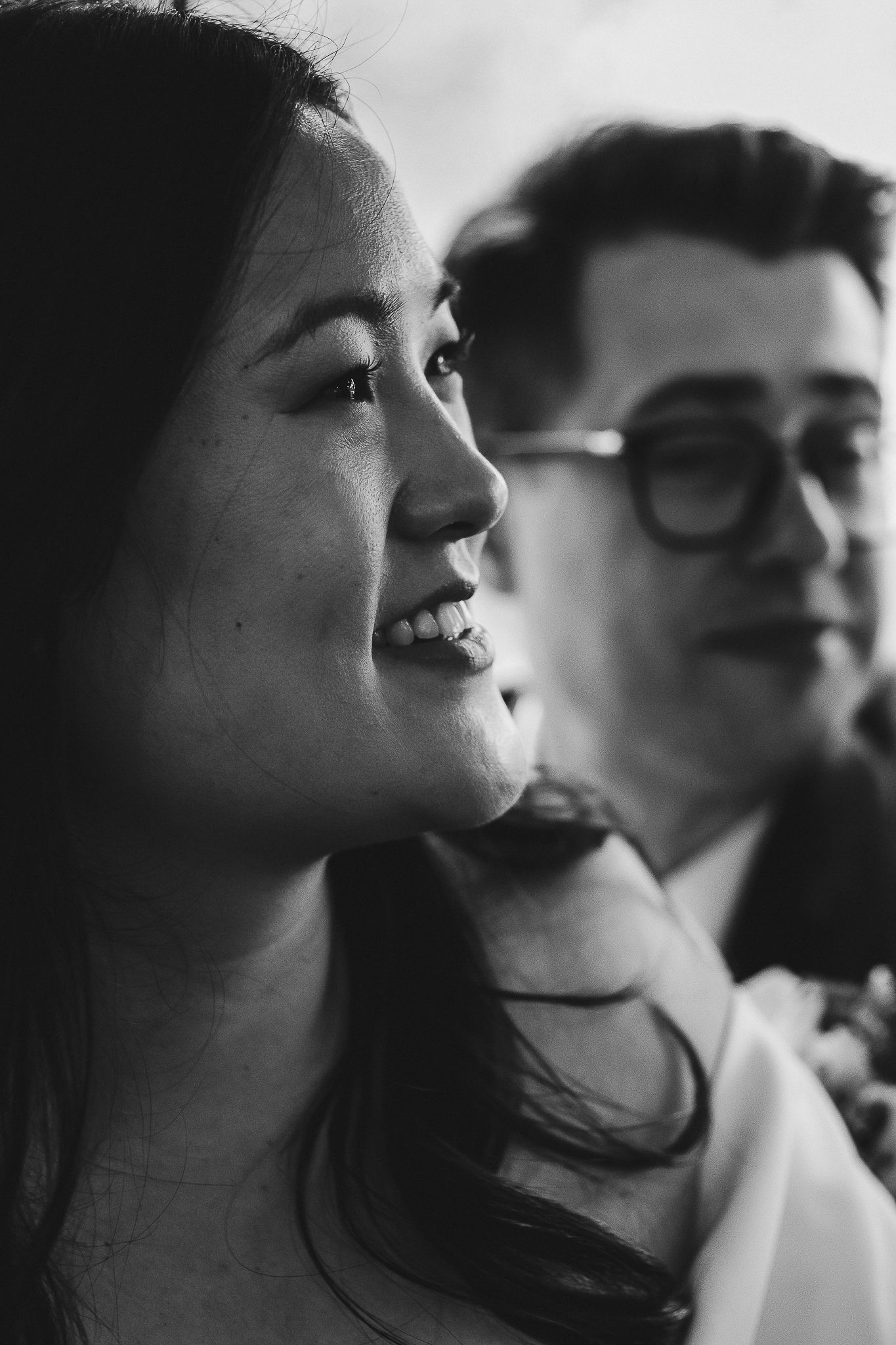 Intimate black and white portrait of two people engaged in candid conversation with smiles and soft lighting.