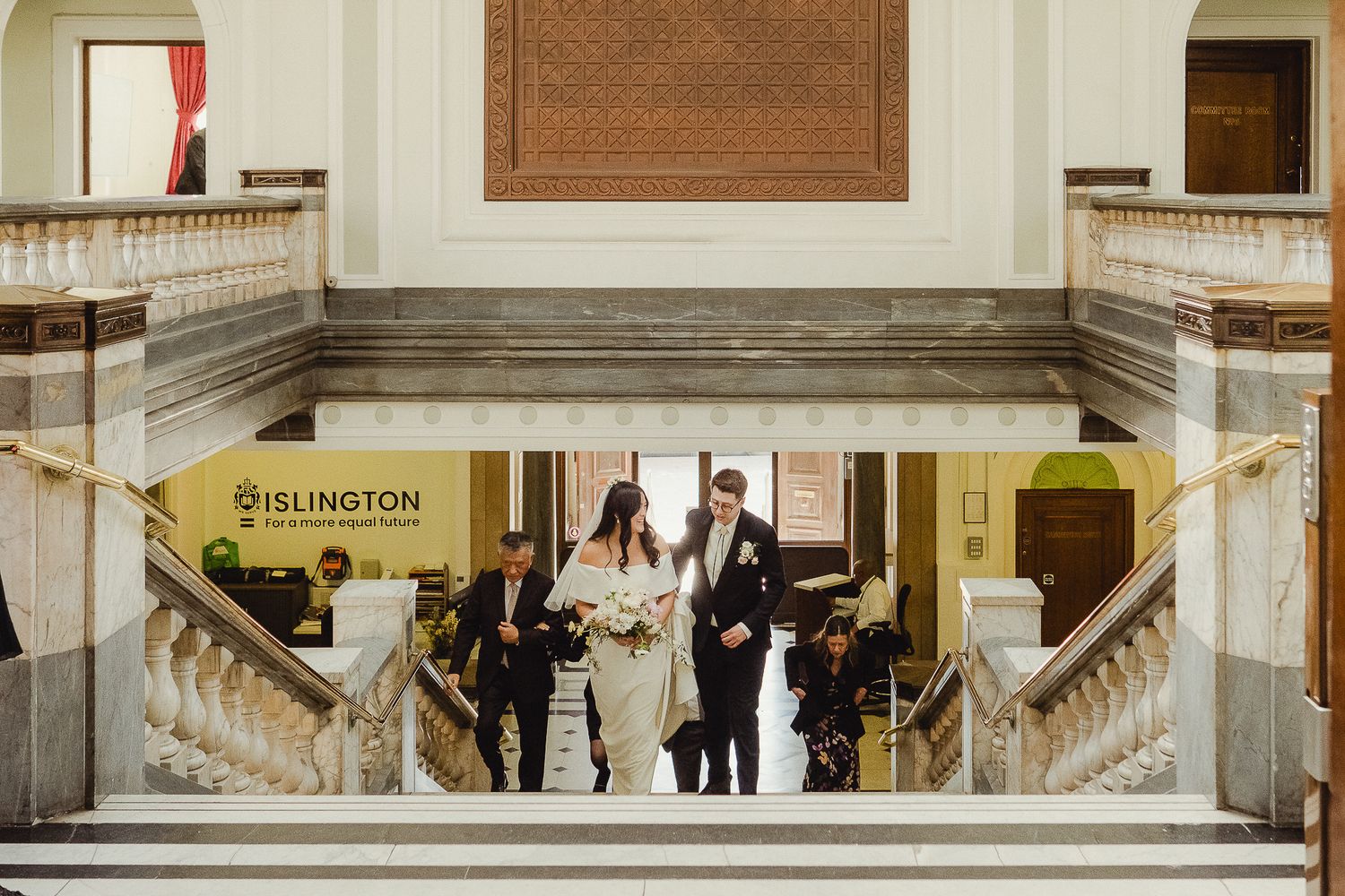 Elegant venue interior with marble staircases framing lower level entrance and architectural details.