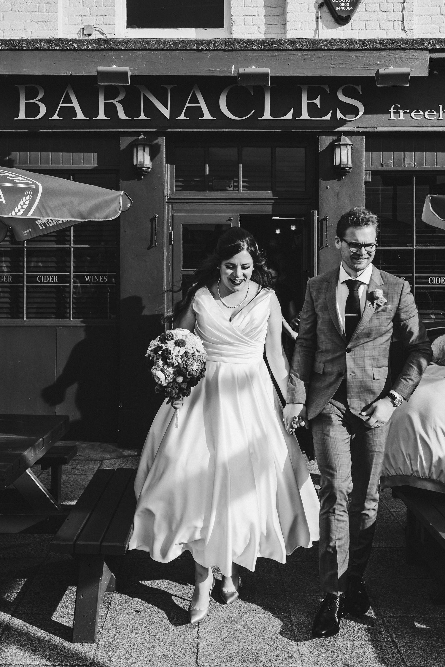 Couple exiting Barnacles restaurant in vintage-inspired wedding attire.