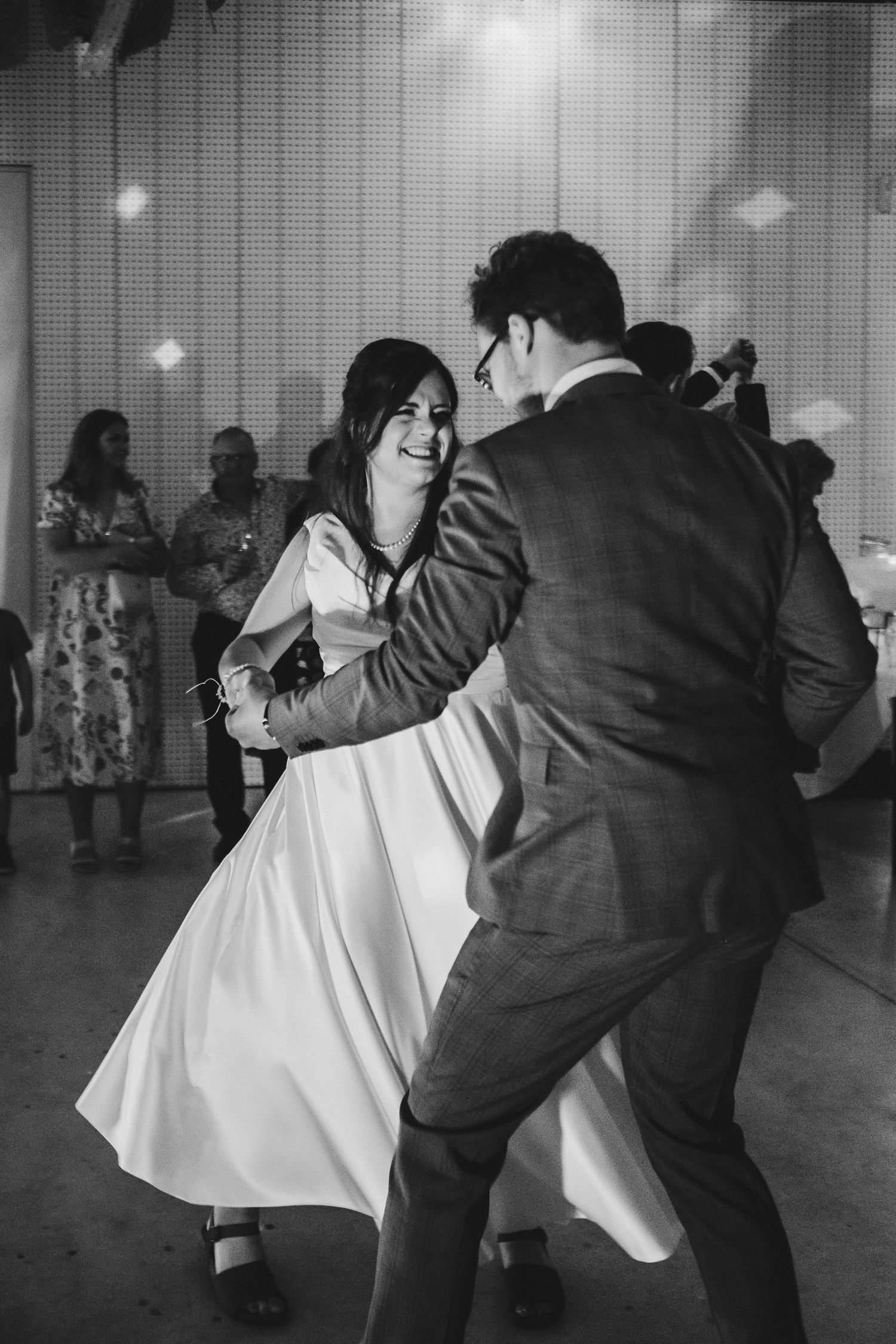 Couple dances together at wedding reception in black and white photograph.