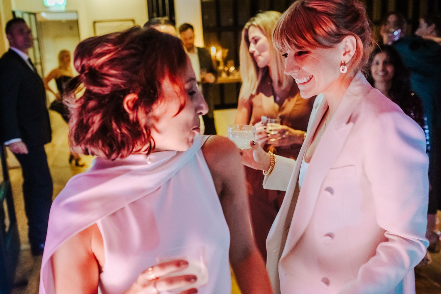 Two people sharing a joyful conversation at an indoor party.