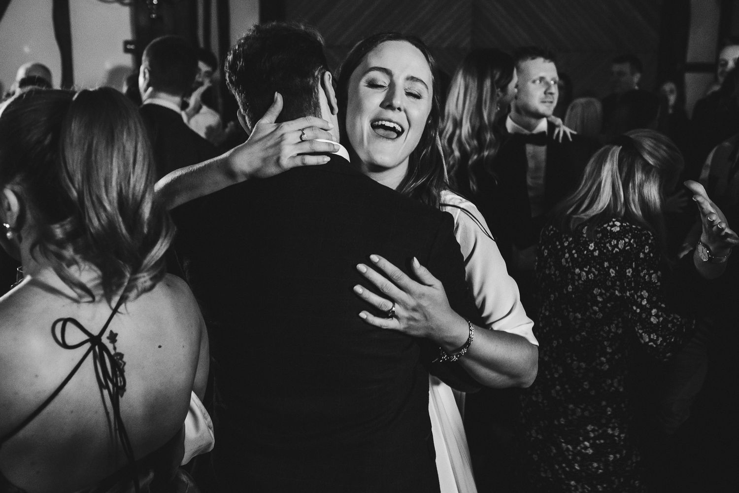 Black and white photo captures joyful dancing at wedding celebration.
