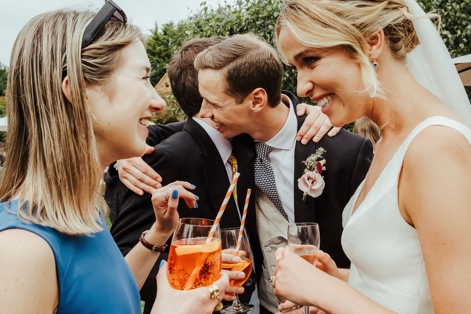 Wedding guests sharing drinks and laughs during outdoor celebration.