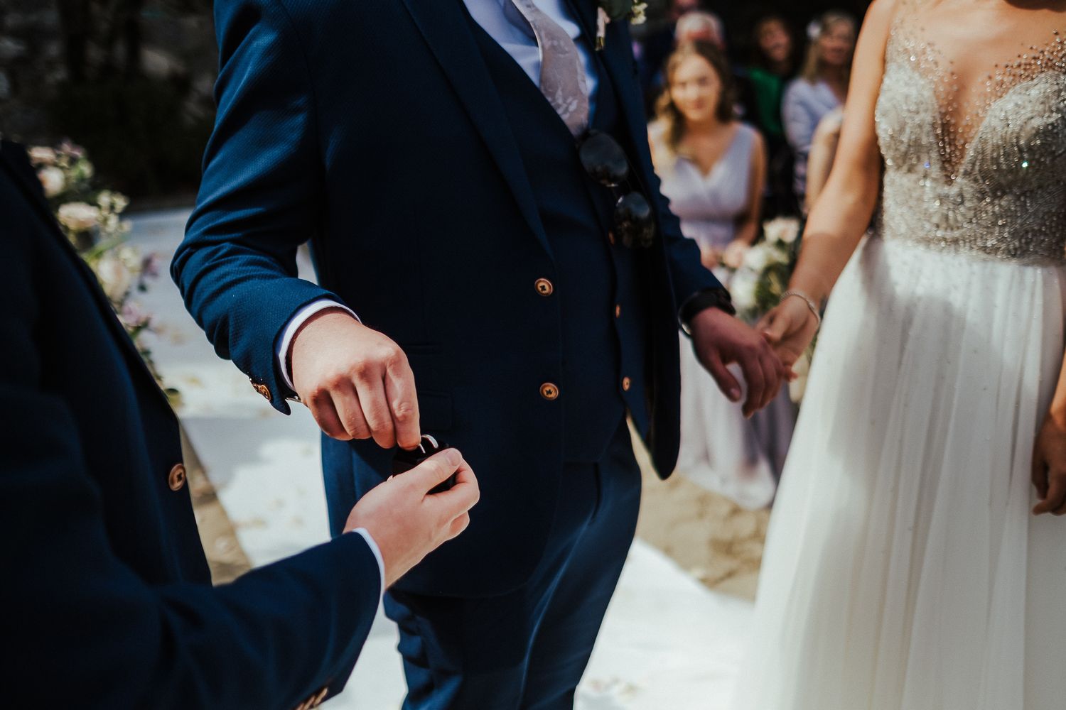 Close-up of wedding ceremony details showing formal attire and hands.