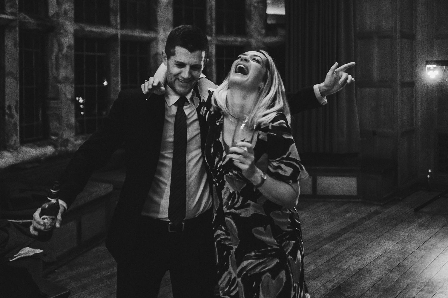 Black and white photo of a couple laughing and dancing at an evening celebration.