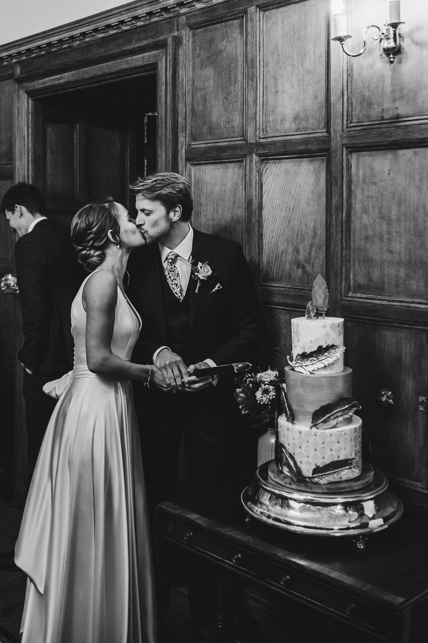 Newlyweds share an intimate moment while cutting their elegant three-tiered wedding cake at their reception.