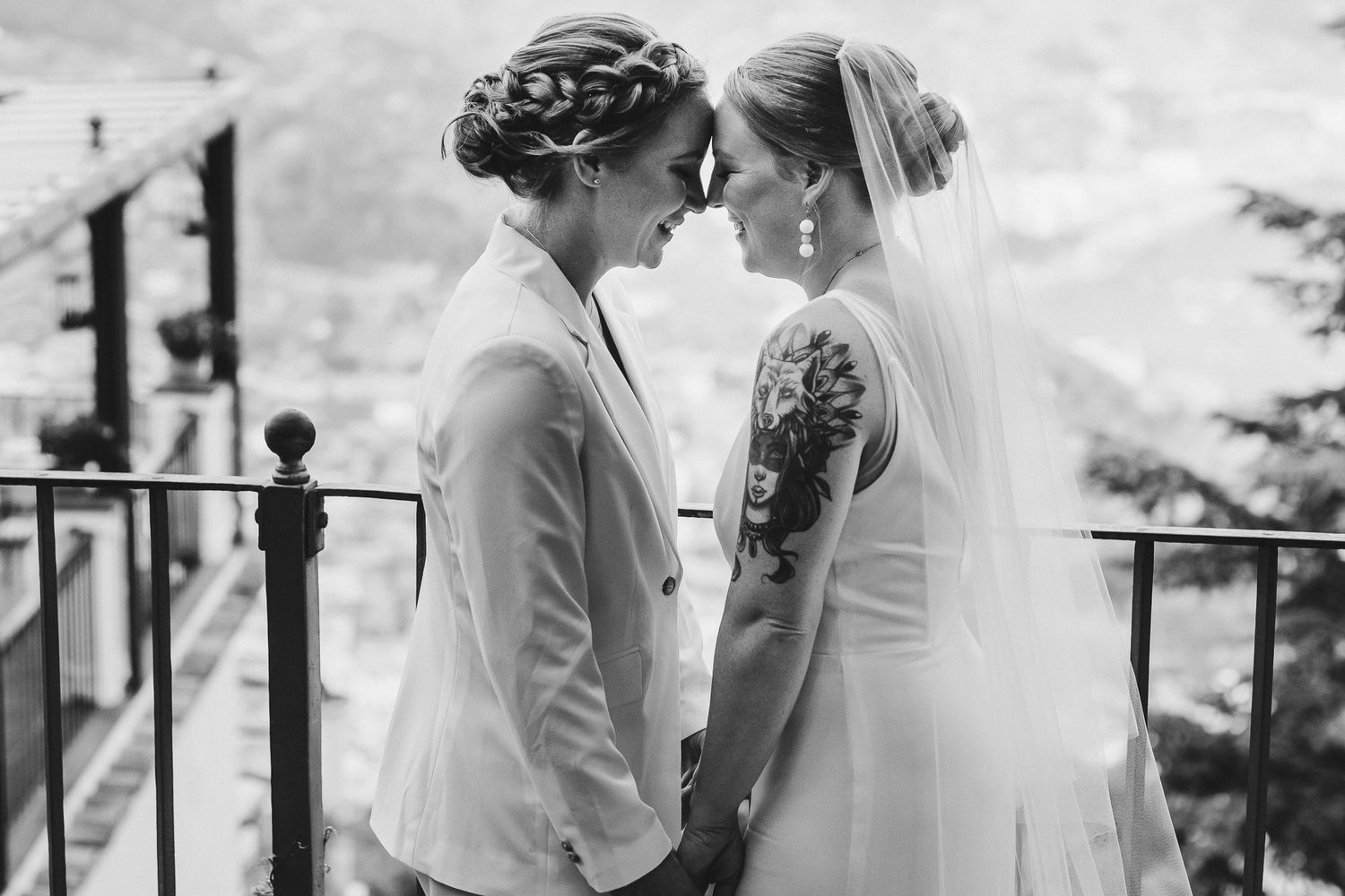 Black and white intimate portrait of newlyweds sharing a tender moment on a balcony.