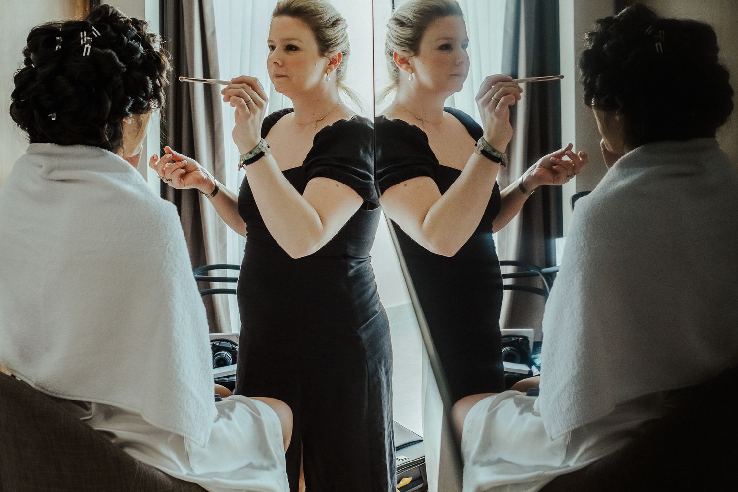 Person in black dress stands between mirrors creating a reflection effect.