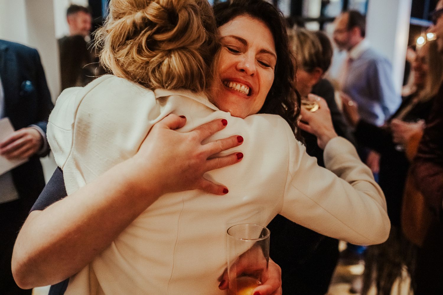 Two people share an emotional embrace at a wedding celebration.