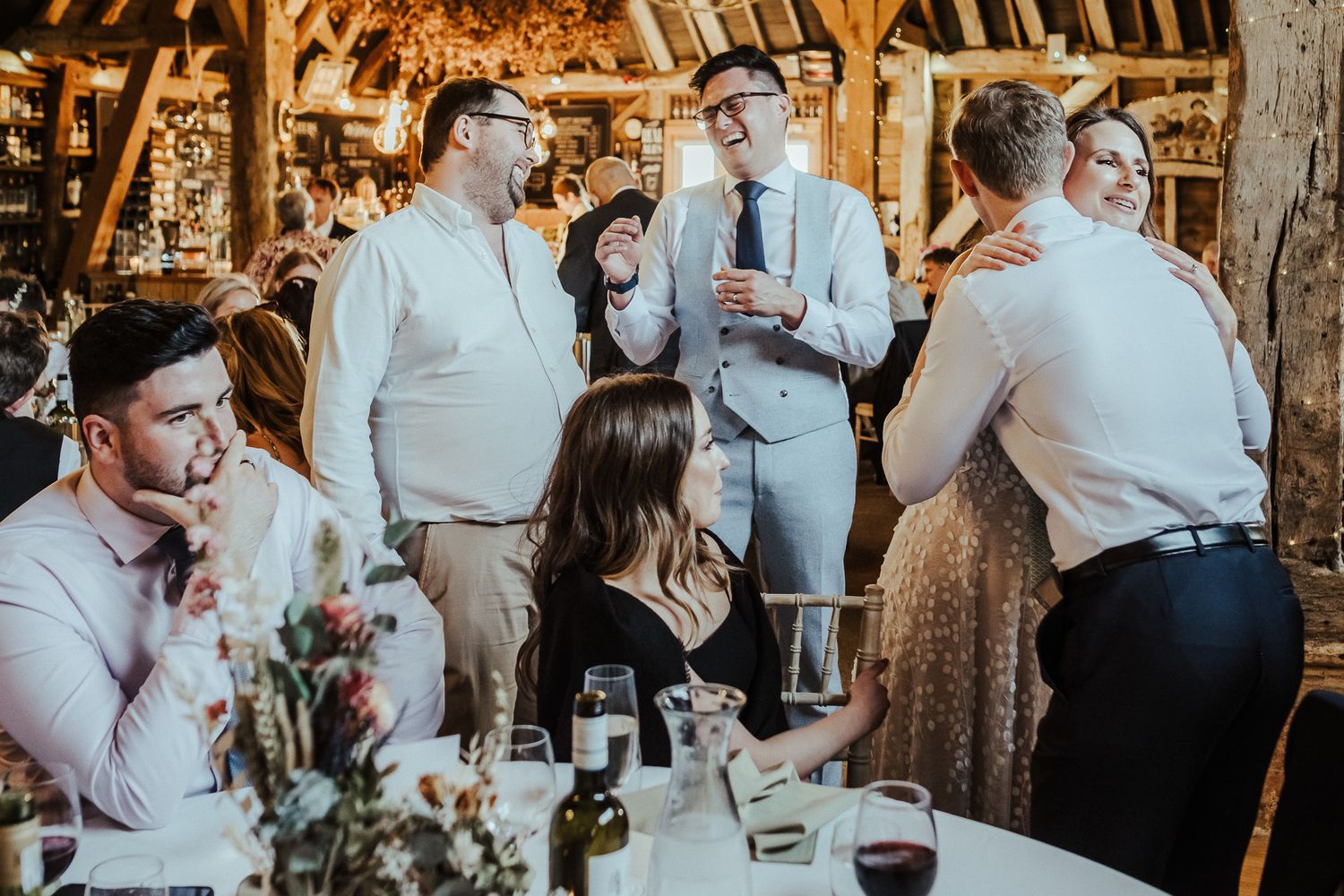 Wedding reception gathering in rustic barn setting with guests mingling.