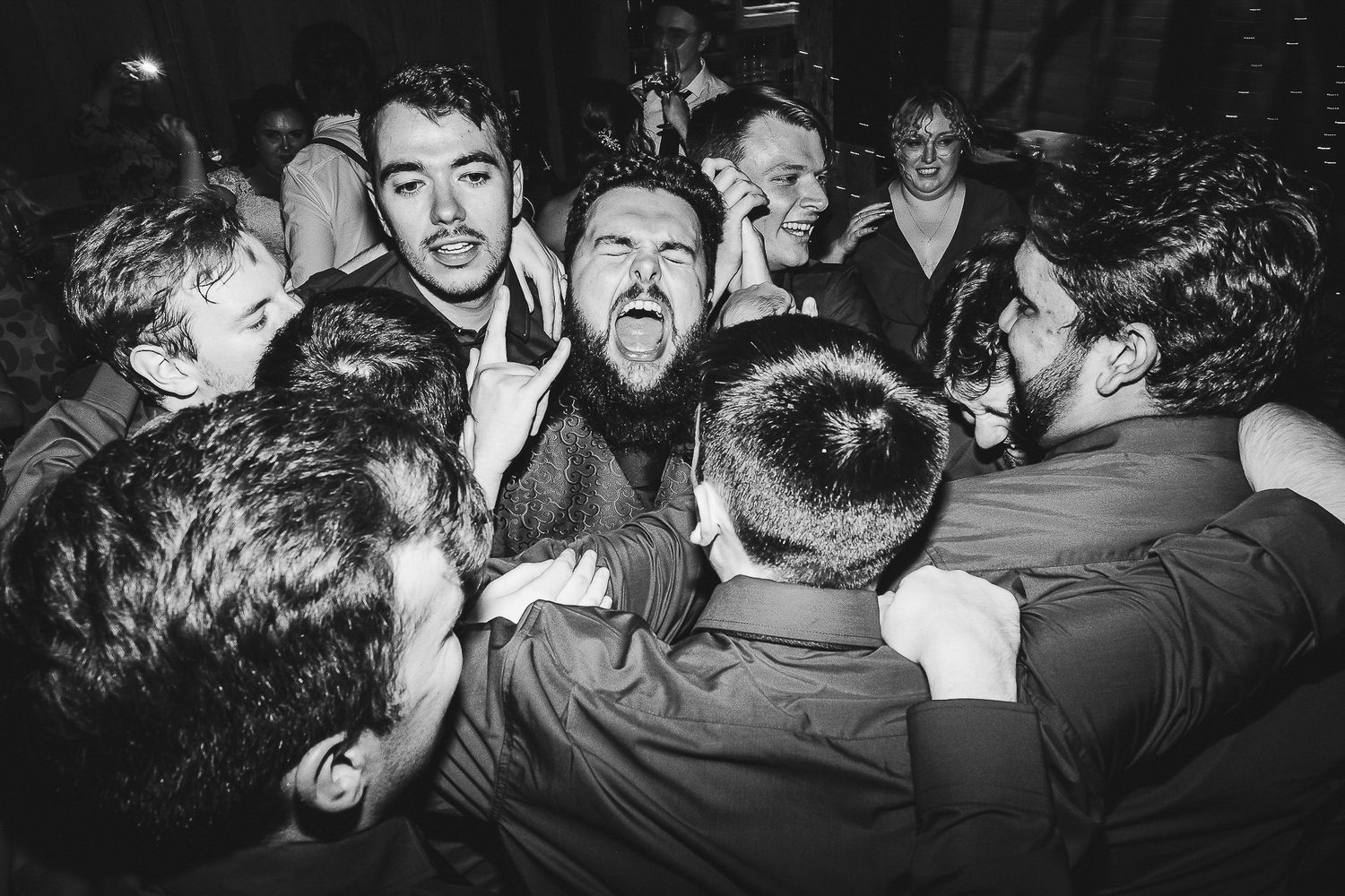 Black and white photo of energetic group huddle with excited expressions.