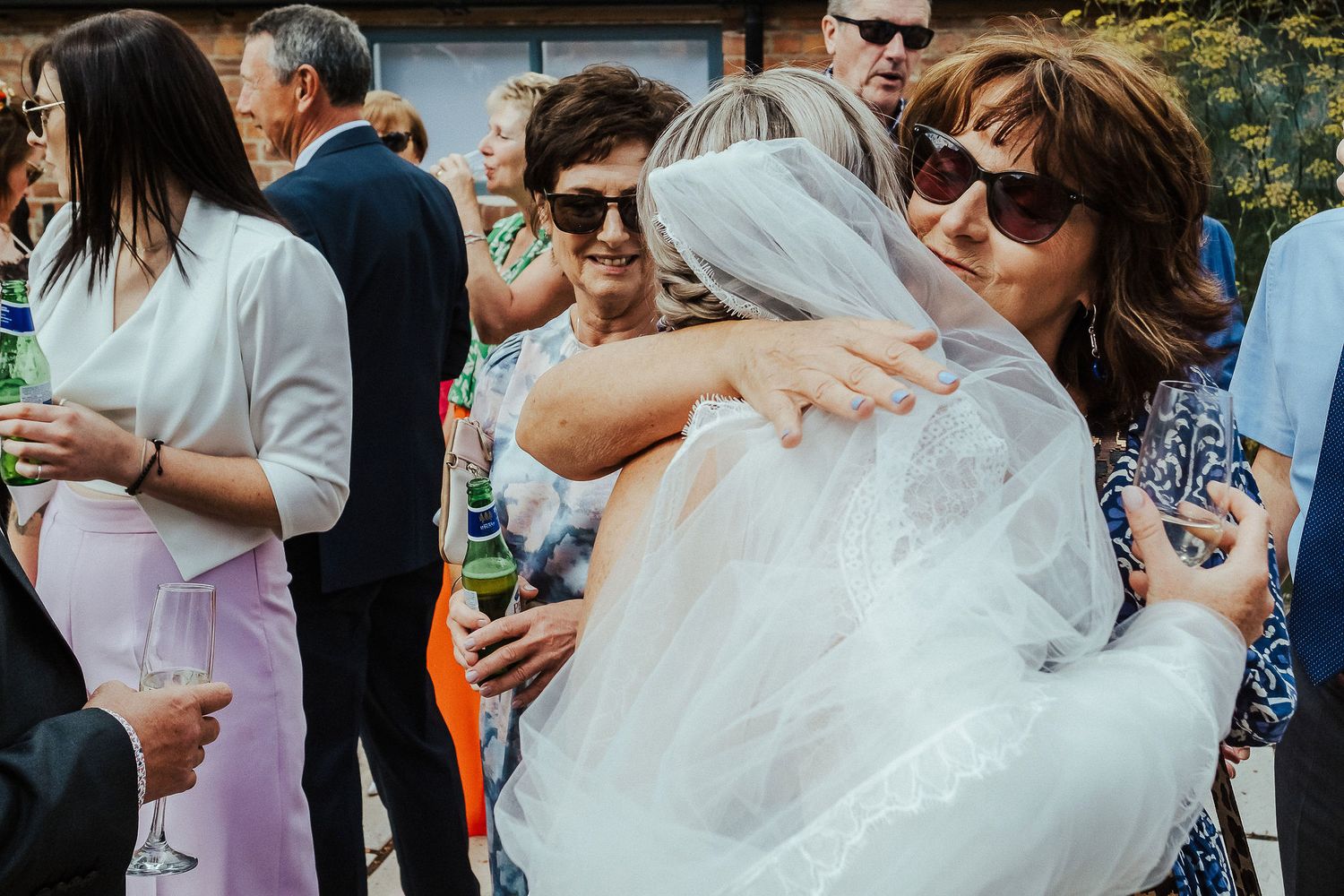 Guests sharing warm hugs during an outdoor wedding reception.