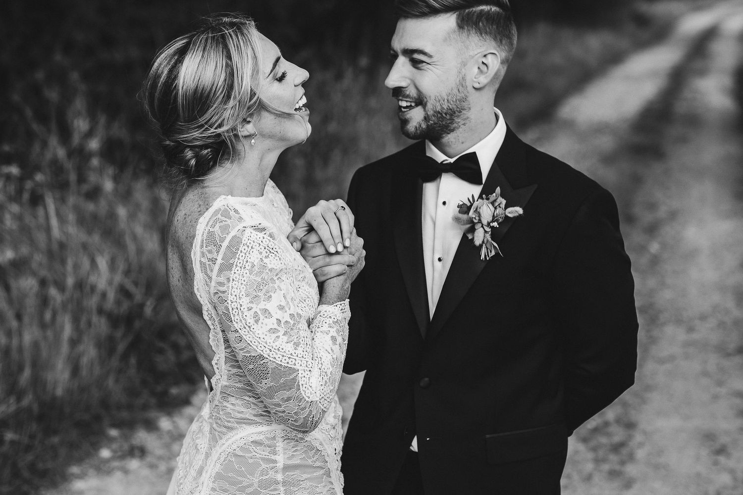 Black and white portrait of newlyweds laughing together on their wedding day.