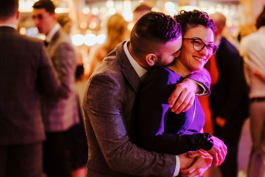 Couple sharing an intimate dance moment under purple lighting at an evening celebration.