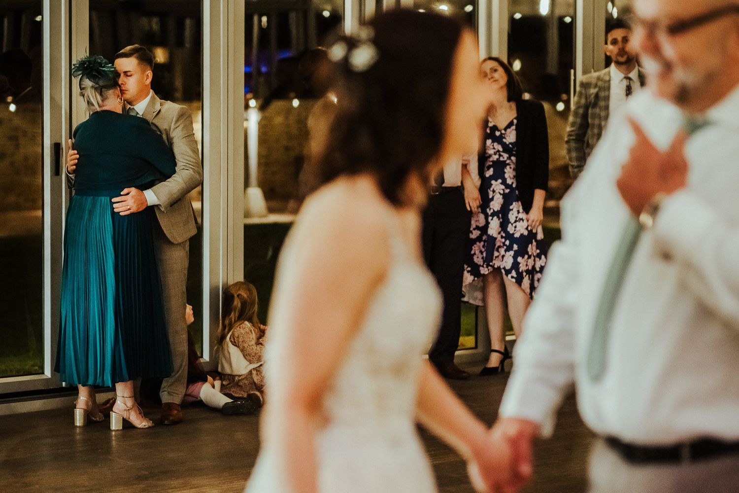 Couples dancing together during an evening wedding reception with twinkling lights.