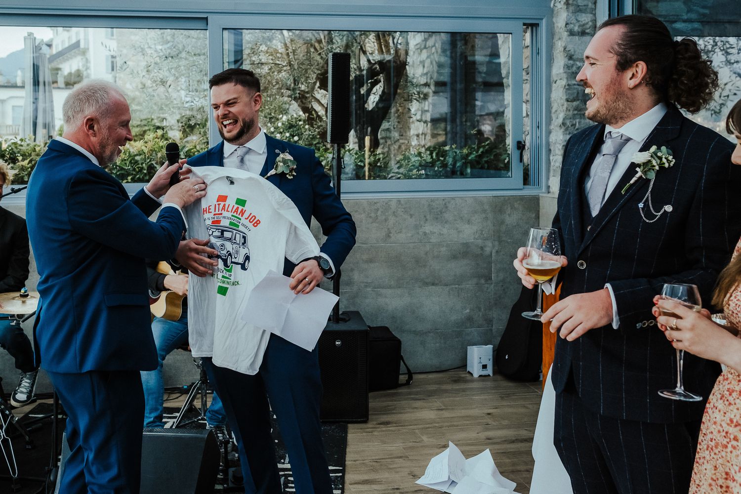 Wedding guests sharing drinks and laughter during an outdoor reception gathering.