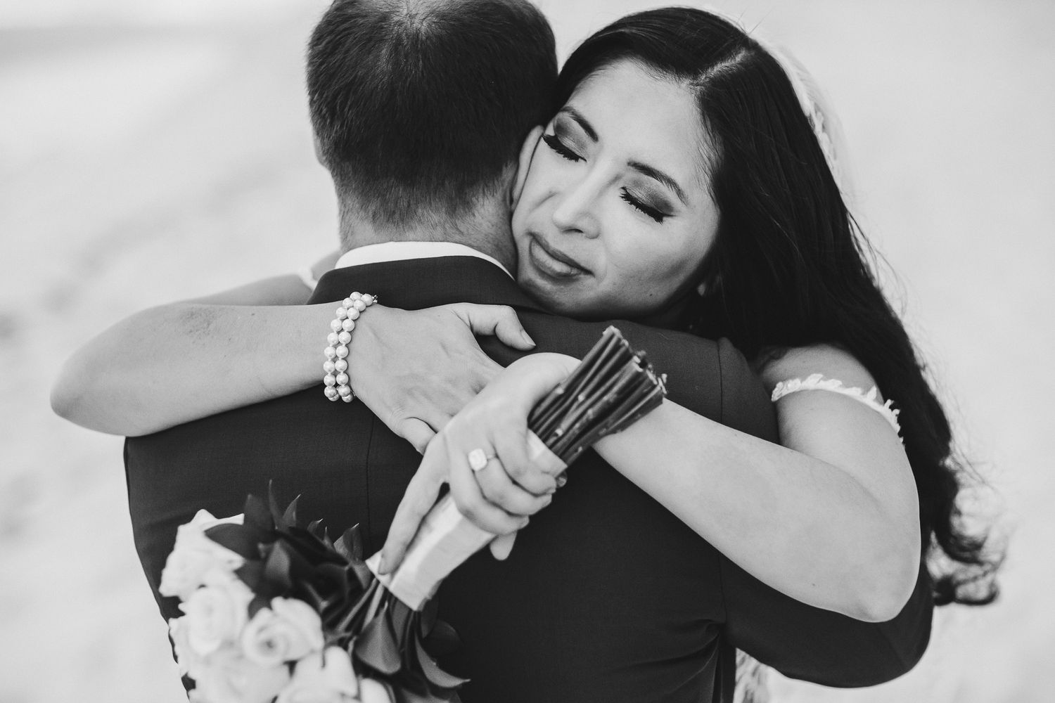 Intimate black and white portrait of newlyweds sharing emotional embrace.