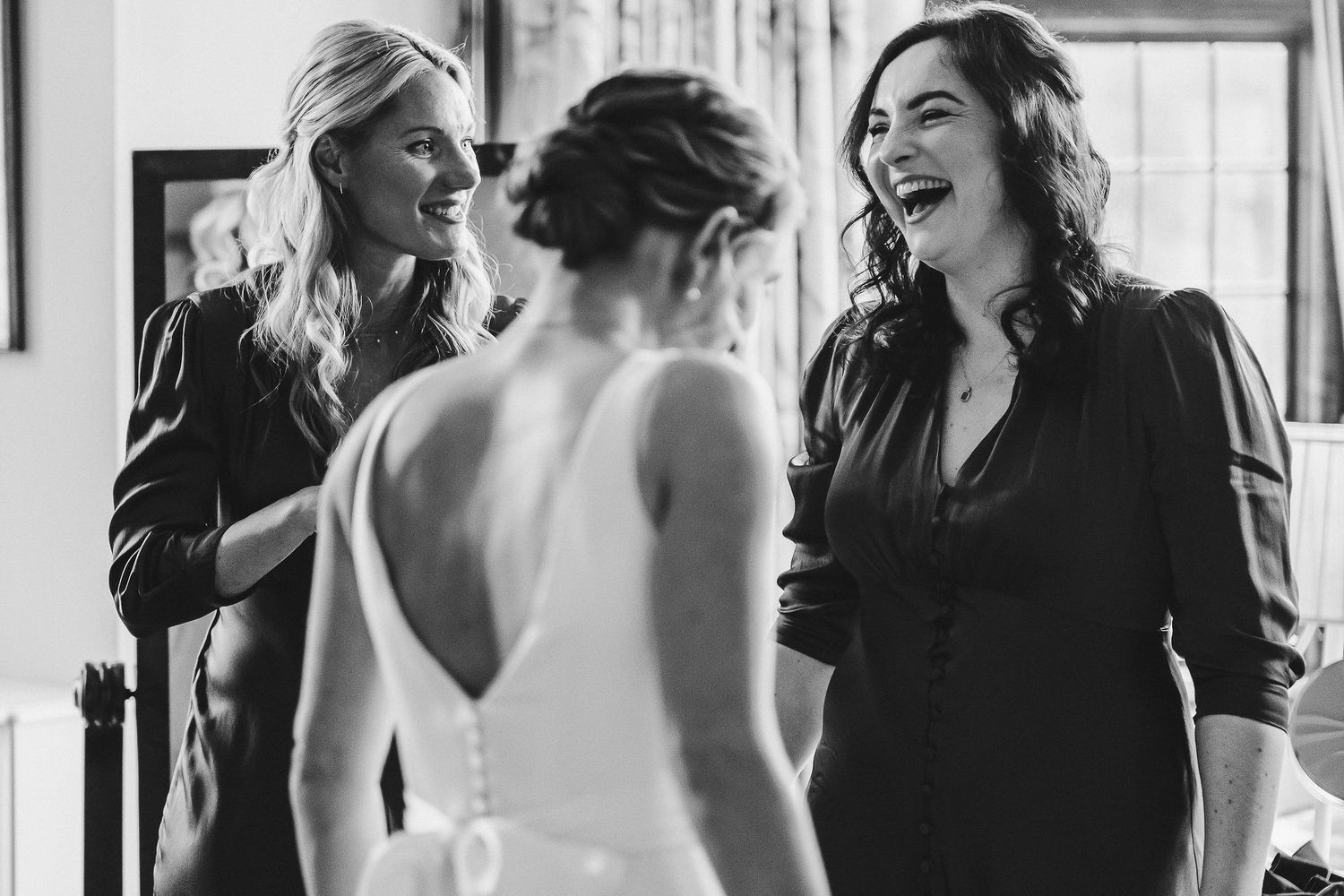 Candid black and white photo of bridal party sharing joyful moment.
