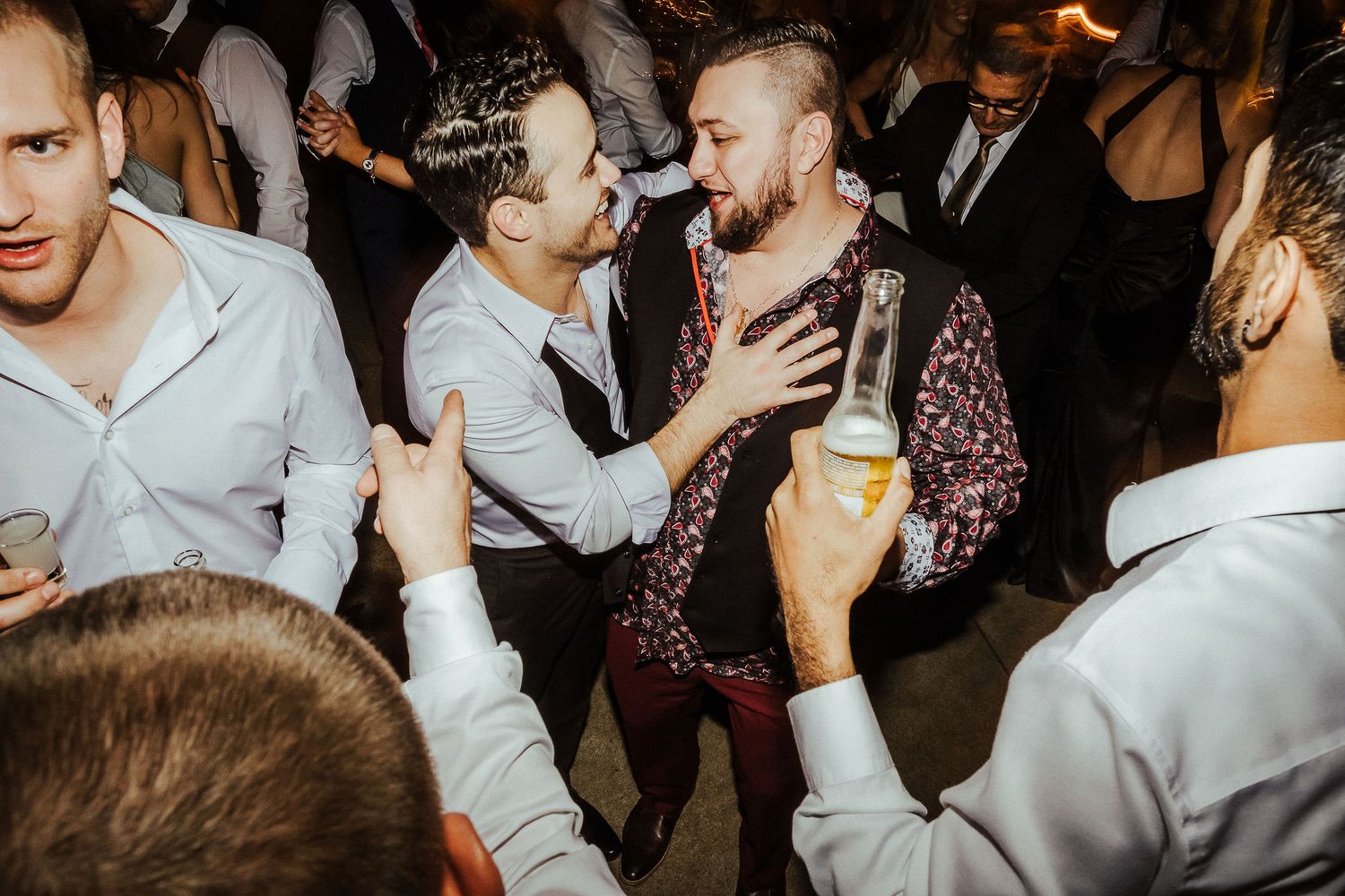 Friends celebrate on a lively dance floor with drinks and laughter at a party.