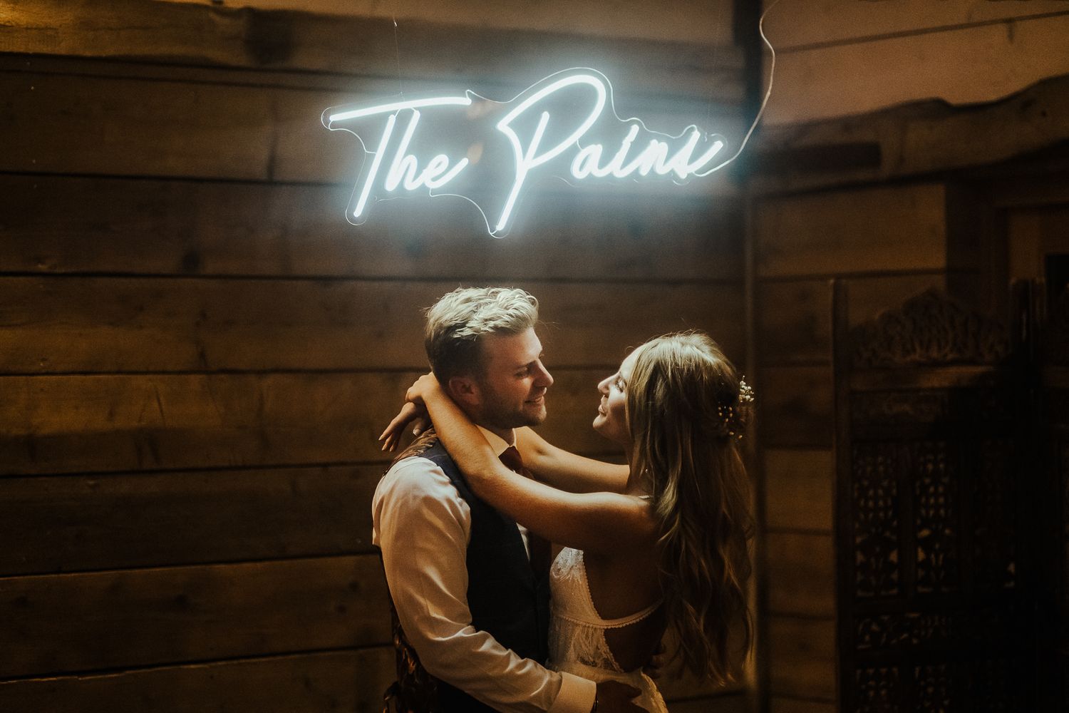 A neon sign reading 'The Paine' glows against a dark wooden wall.