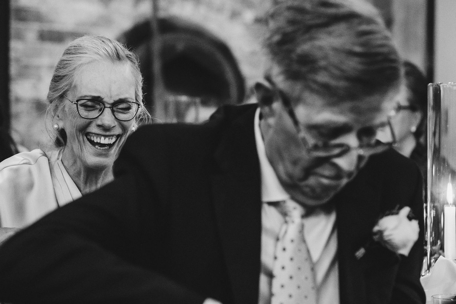 A candid black and white moment of laughter and joy shared during a formal event.