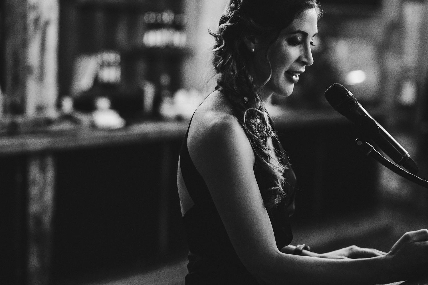 Performer in an elegant dark dress sings passionately at a microphone during an evening event.