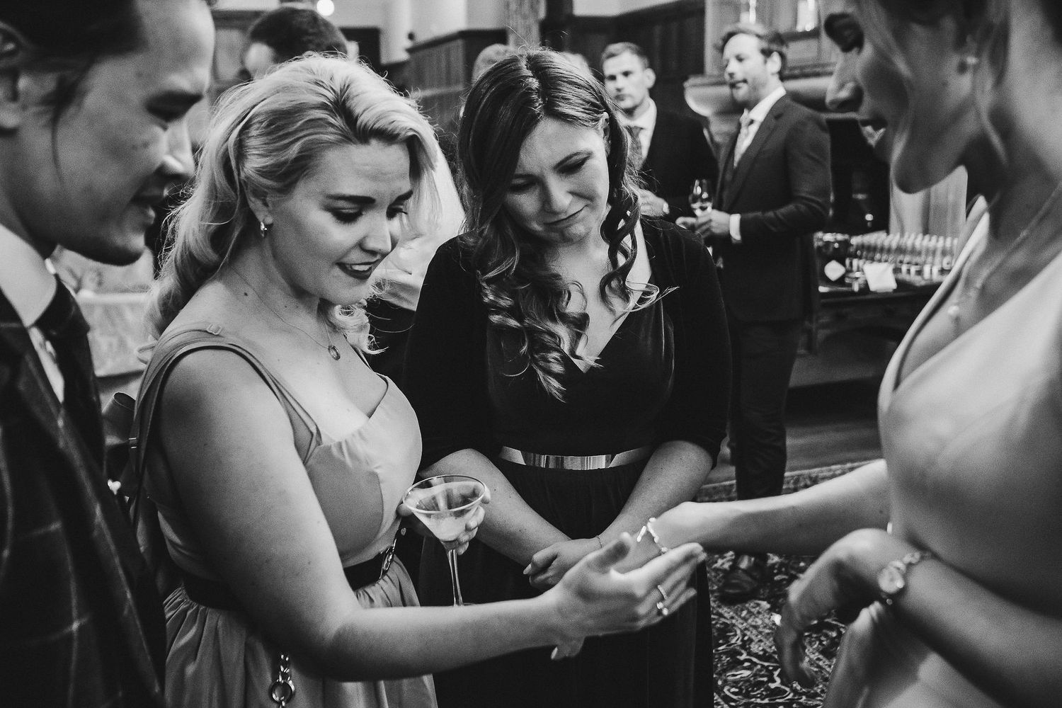 Wedding celebration captured in black and white as guests gather for drinks and conversation.