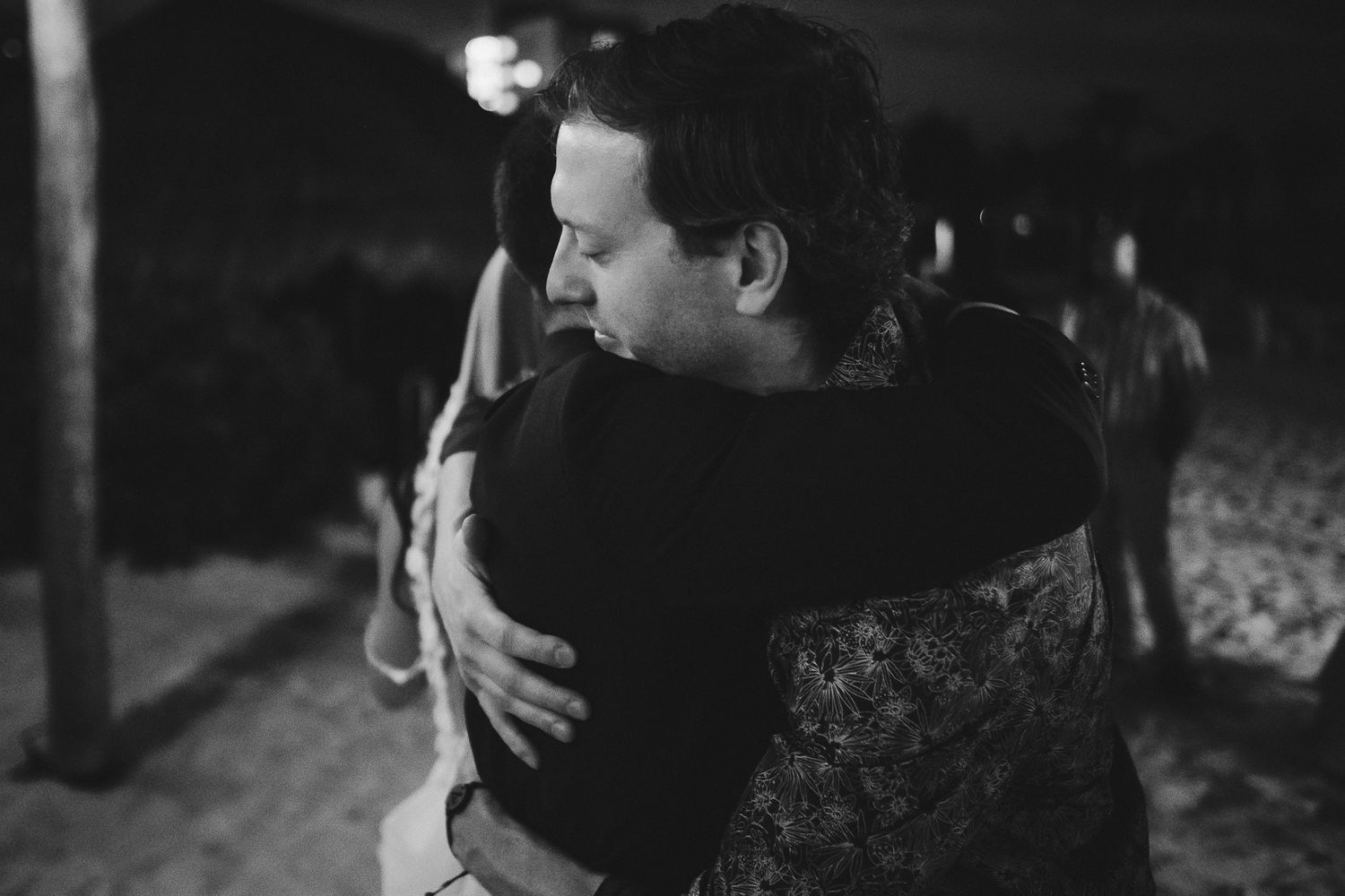 An emotional embrace captured in black and white at a nighttime event.
