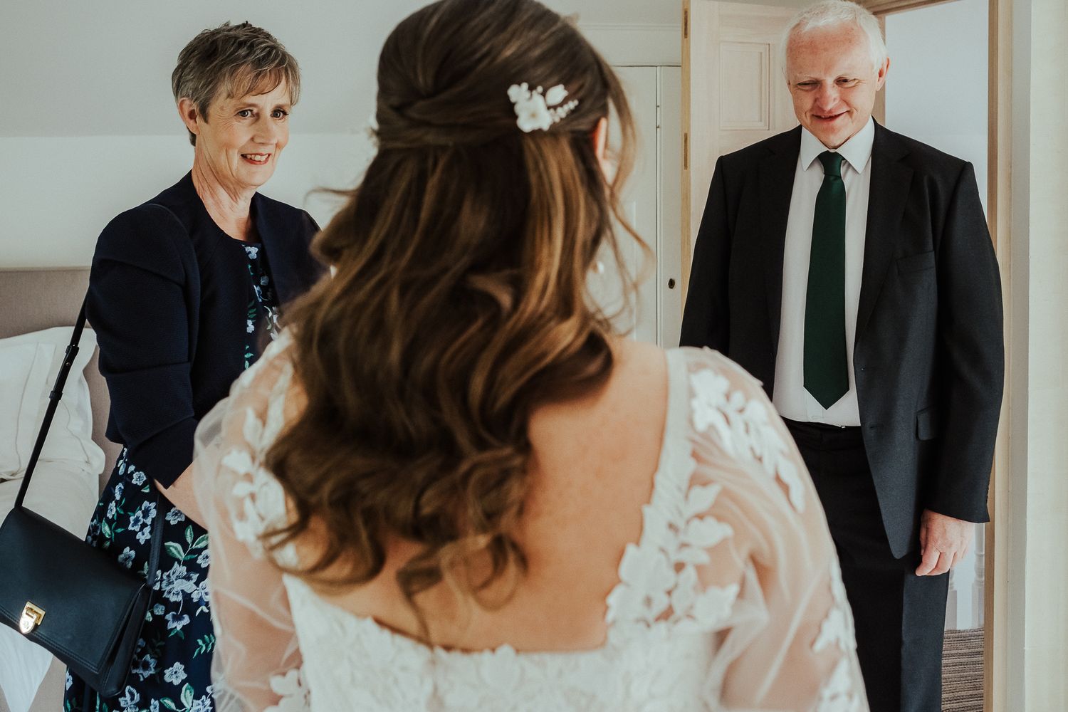 Wedding preparation scene with guests and formal attire in a sunlit room.