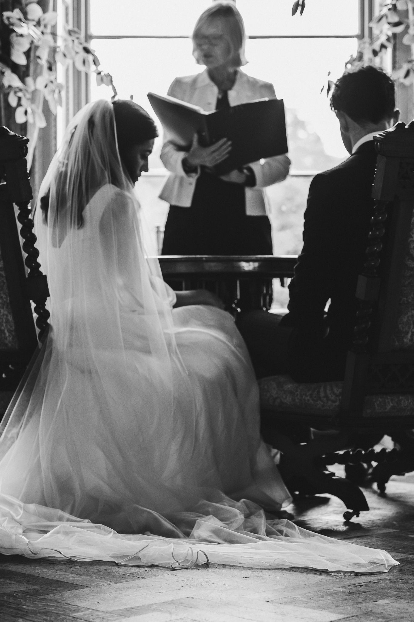 A silhouette of a wedding ceremony with bride and officiant reading from a book.