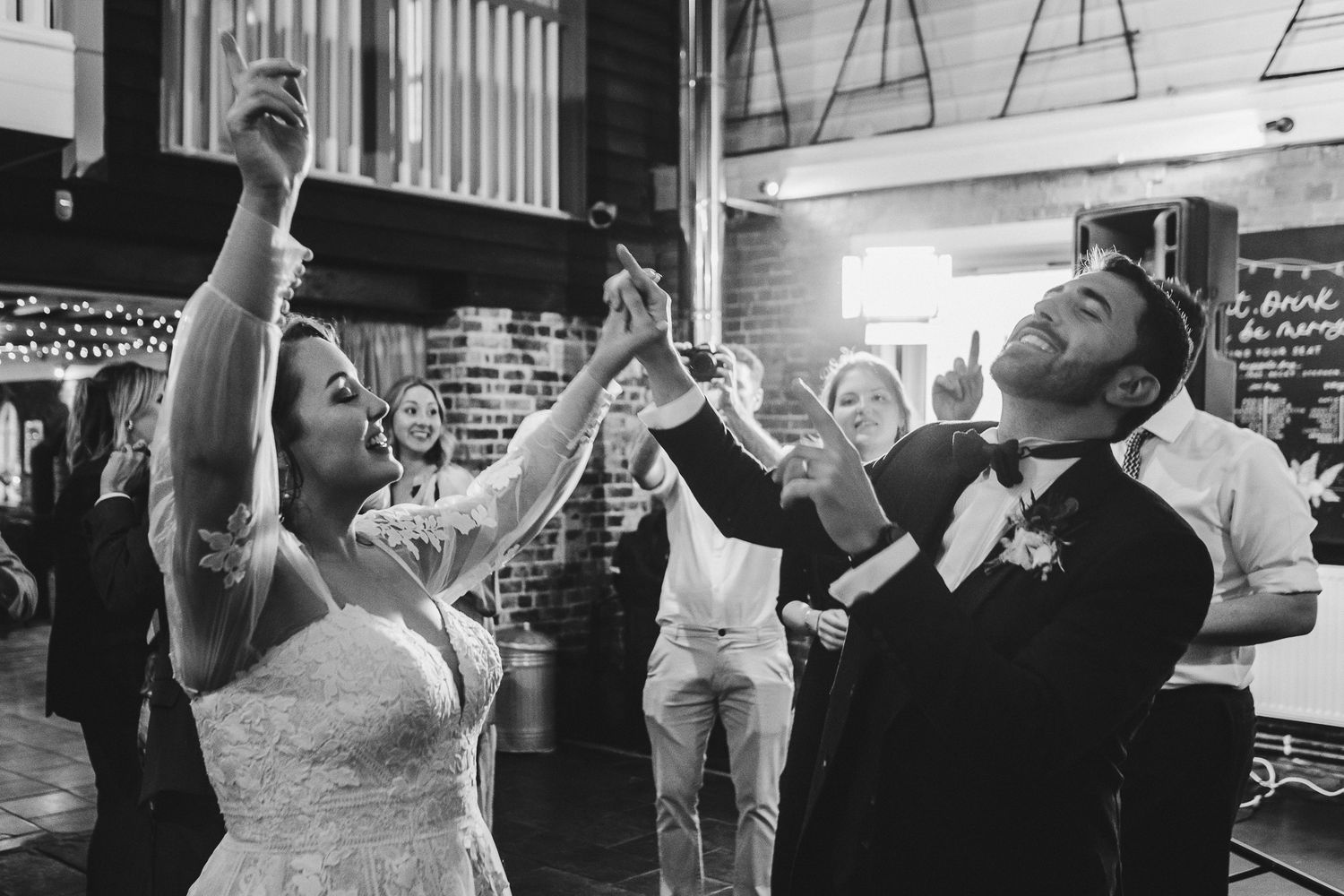 Joyful celebration moment at a wedding reception with people raising their hands in excitement.