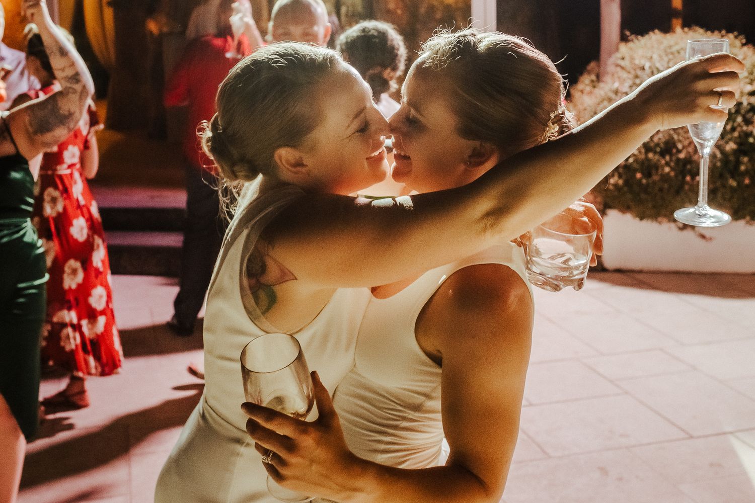 Two people in white dresses sharing an intimate dance moment at a celebration.