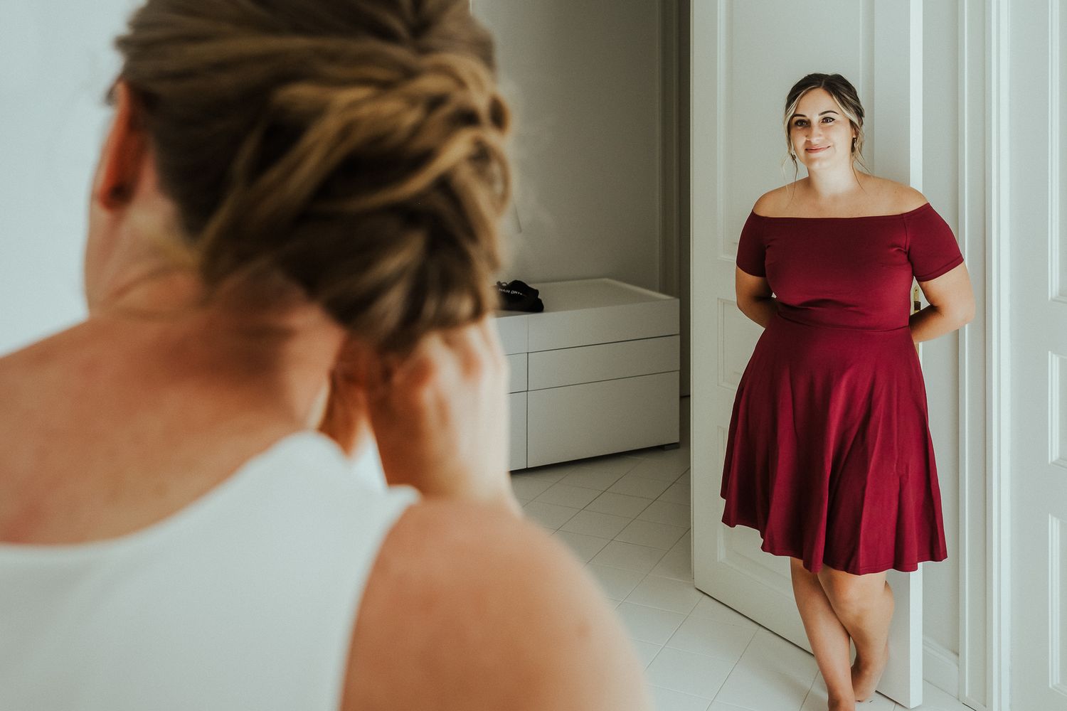 Wedding preparation sequence showing someone in a burgundy dress by a bright window.