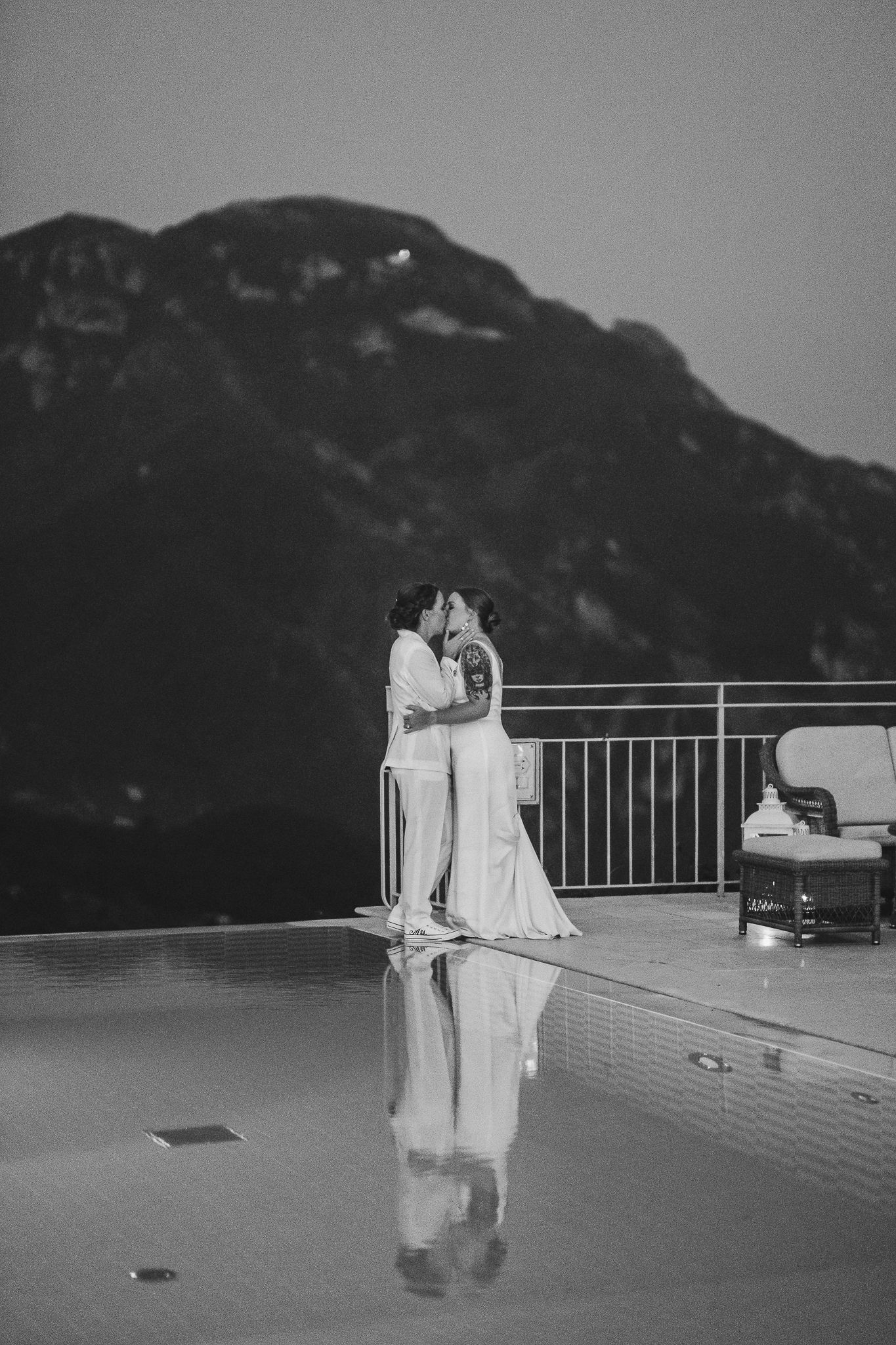 Black and white wedding portrait on rooftop terrace overlooking mountain landscape.