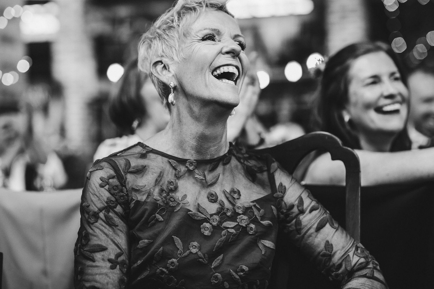 Guests laughing during emotional wedding reception moments.