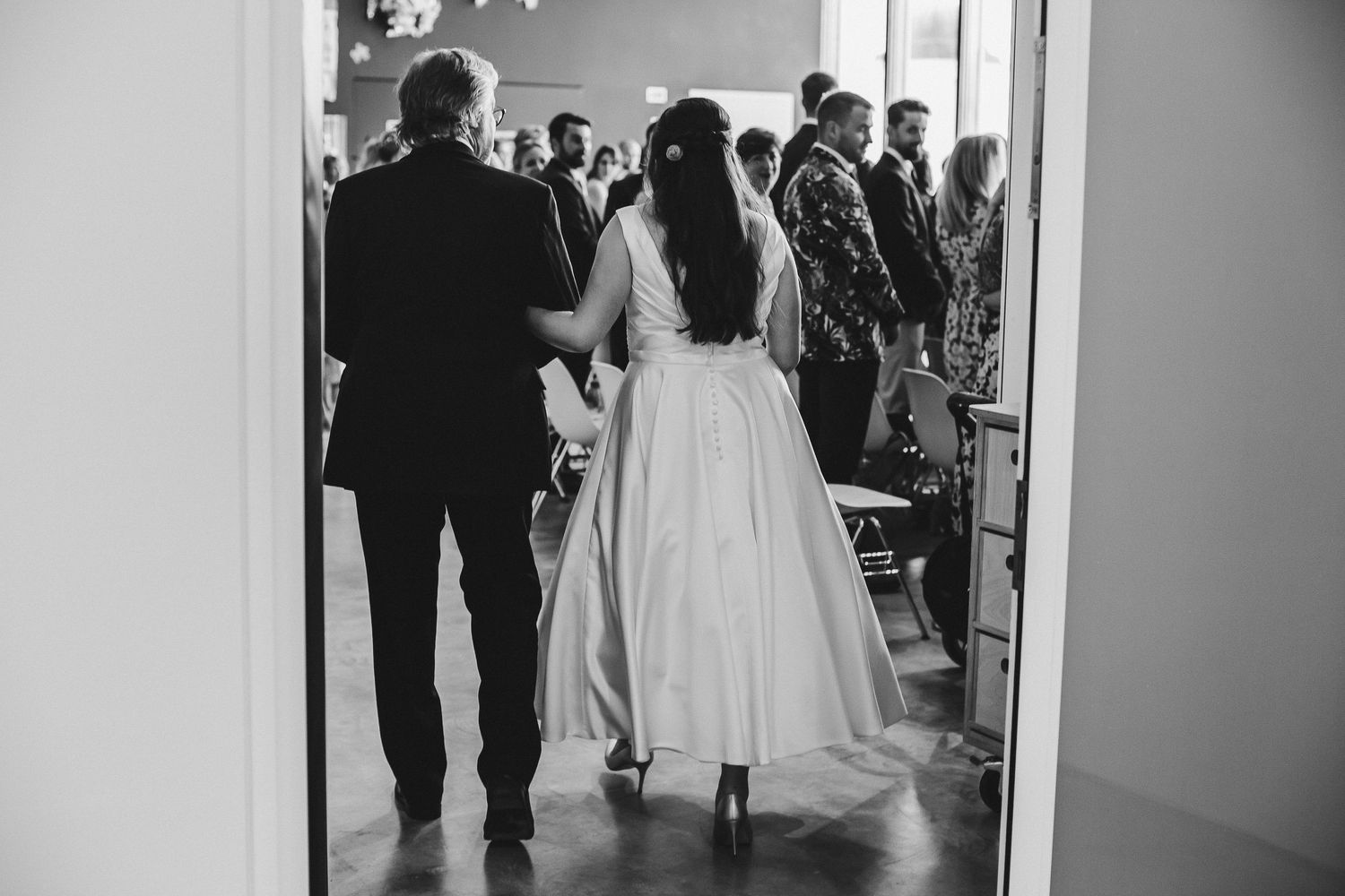 Black and white photo captures a wedding couple entering their reception venue.
